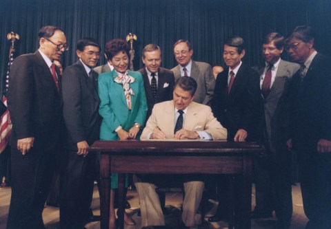 Ronald_Reagan_signing_Japanese_reparations_bill 1988